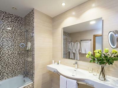 Bagno moderno con lavabo, grande specchio, vasca da bagno e piastrelle a mosaico