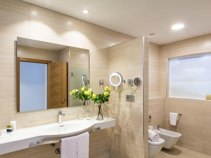 Bagno moderno con grande specchio, lavabo doppio e composizione floreale.