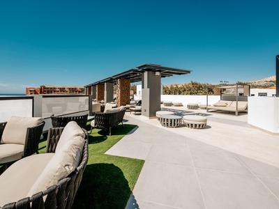 Moderne Dachterrasse mit Sitzgruppen, Pergola, weißen Wänden und klarem blauem Himmel.