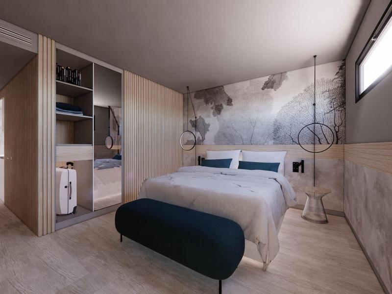 Camera d'albergo moderna con letto matrimoniale, armadio e murale con mappa del mondo.