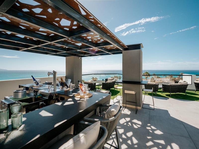 Bar moderna con posti a sedere e vista mare su una terrazza soleggiata.