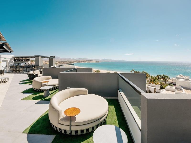 Terrazza sul tetto con posti a sedere moderni e vista sul mare sotto un cielo limpido.