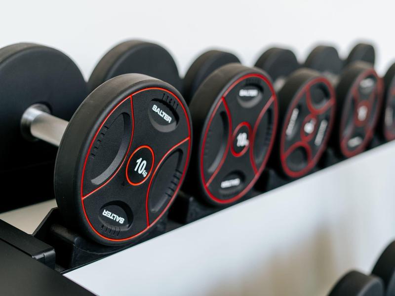 Fila di dischi pesi neri e rossi in una palestra.