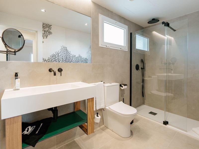 Bagno moderno con lavabo bianco, WC e doccia walk-in con parete in vetro.