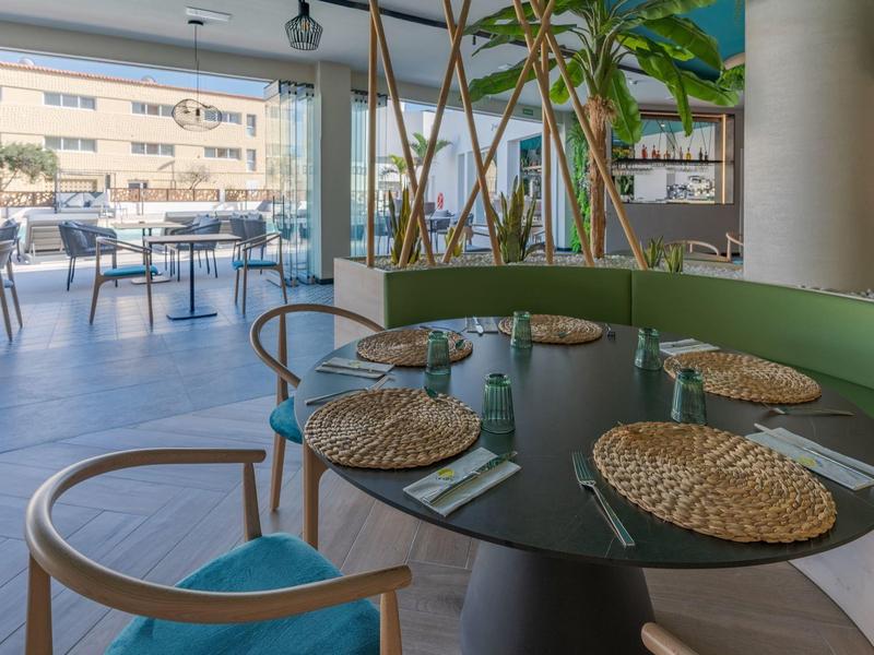 Ristorante moderno con tavoli rotondi, sedie di legno e vista su una terrazza.