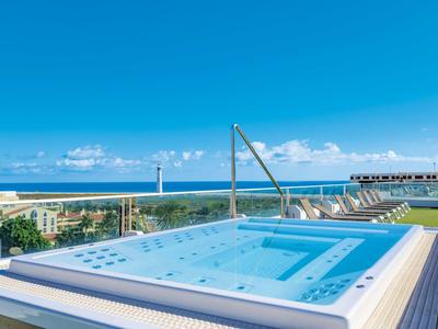 Vasca idromassaggio su terrazza sul tetto con vista mare e cielo azzurro limpido.