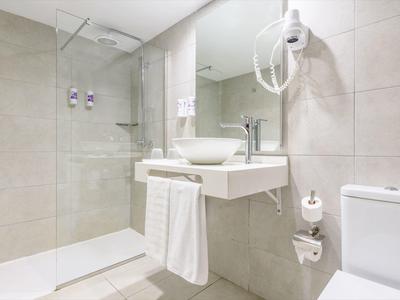 Bagno moderno con doccia walk-in, lavabo, WC e asciugacapelli.