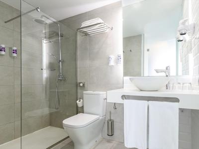 Bagno moderno con doccia walk-in, WC e lavabo con asciugamani.