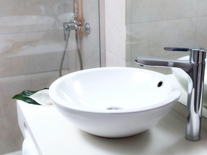 Lavandino bianco moderno con rubinetto cromato in un bagno luminoso.