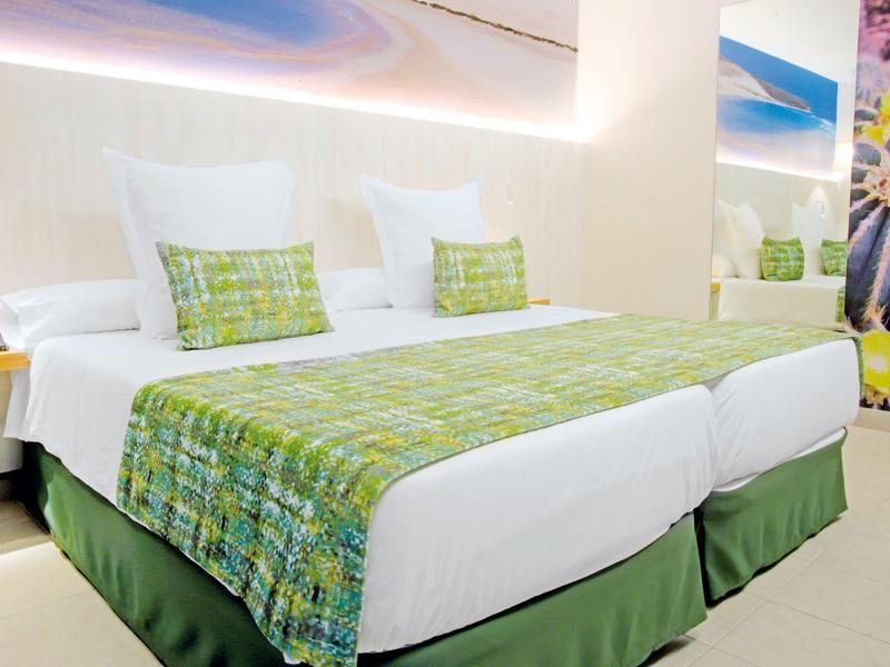 Camera d'hotel moderna con due letti singoli e arredamento verde e bianco.