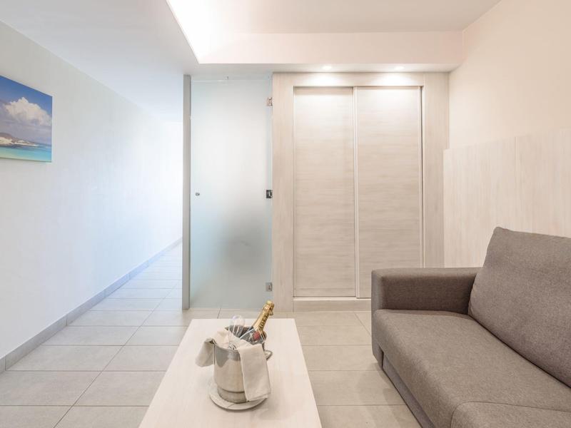 Stanza moderna con divano grigio, tavolo bianco e design minimalista luminoso.