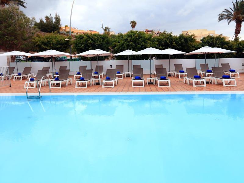 Piscina limpida con lettini e ombrelloni bianchi nell'area piscina dell'hotel.