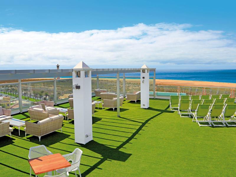 Terrazza sul tetto con lettini e zone soggiorno con vista mare sotto un cielo sereno
