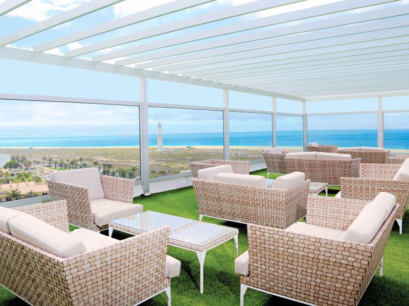 Terrazza sul tetto con poltrone in rattan e vista limpida sul mare.