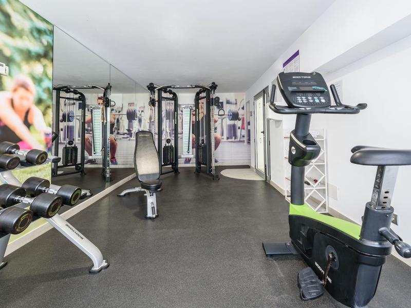 Palestra moderna con varie attrezzature per esercizi e pesi in una stanza luminosa.