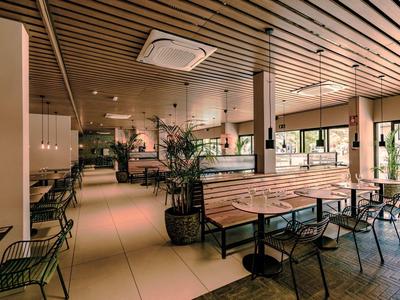 Modernes Café mit Holzdecke, Holzbank, schwarzen Stühlen und großen Fenstern für viel Tageslicht.
