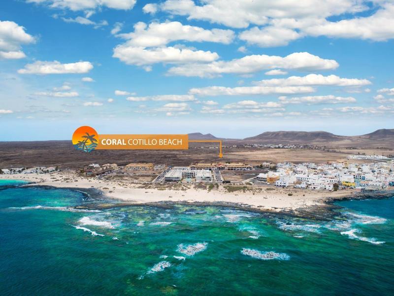 Città costiera con resort hotel, mare turchese, costa rocciosa e cielo parzialmente nuvoloso