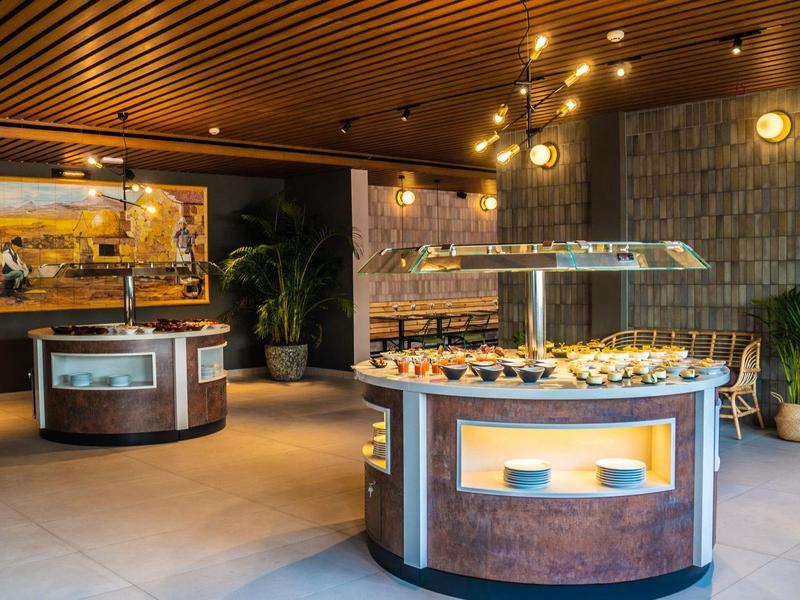 Area buffet in una moderna sala da pranzo dell'hotel con espositori rotondi e illuminazione calda.