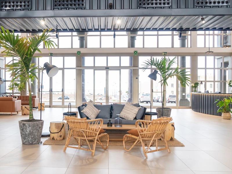 Luminosa hall dell'hotel con posti a sedere moderni, grandi finestre e piante interne