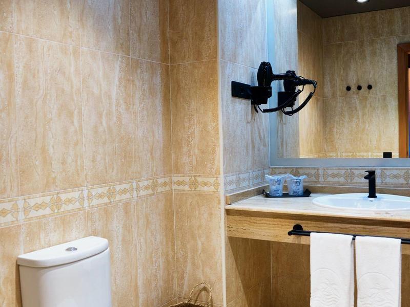 Bagno moderno in hotel con WC, lavabo, specchio e asciugamani.