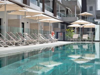 Modern hotel pool with lounge chairs and umbrellas on a quiet day.