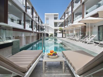 Modern hotel pool with lounge chairs and umbrellas in light colors.