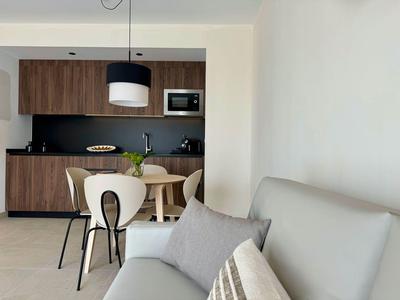 Nowoczesna jadalnia z drewnianymi meblami i białą sofą z poduszkami w pokoju hotelowym.