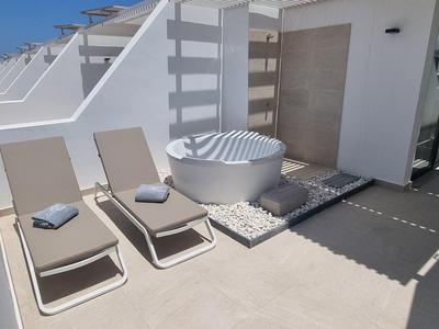 Taras na dachu z dwoma leżakami i jacuzzi pod czystym niebem.