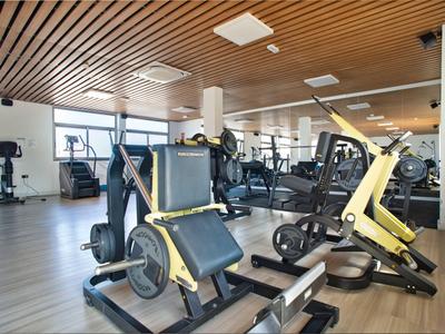 Modern gym with various exercise machines and wooden beam ceiling in a hotel.