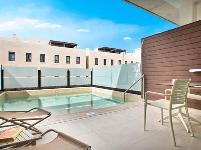 Nowoczesny taras hotelowy z małym basenem, leżakami i miejscem do siedzenia pod czystym niebem.