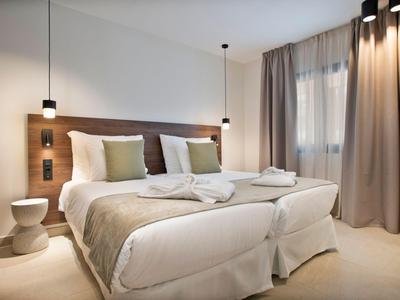 Nowoczesny pokój hotelowy z dwoma pojedynczymi łóżkami, ciepłymi drewnianymi akcentami i miękkim oświetleniem.