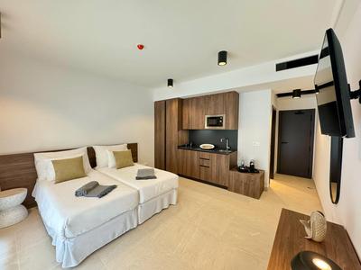 Nowoczesny pokój hotelowy z dwoma łóżkami, telewizorem na ścianie i minimalistycznym wystrojem.