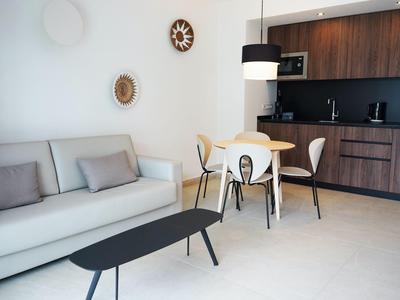 Modern living area with gray sofa, black table, and wooden kitchen.