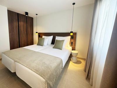 Modern hotel room with double bed, wooden furniture, and soft lighting.