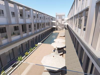 Bright terrace with seating and umbrellas between modern hotel buildings.