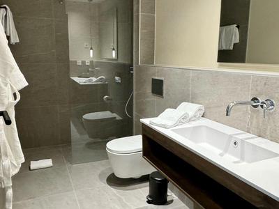 Bagno moderno con doccia, toilette e doppio lavabo in toni neutri grigi.