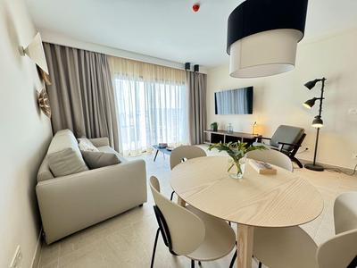 Soggiorno moderno con divano, tavolo rotondo e TV a parete.