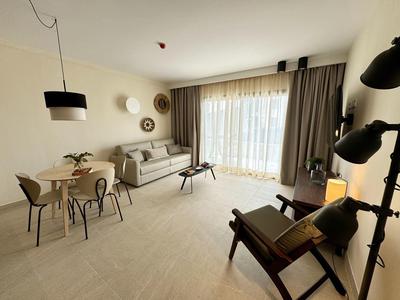 Soggiorno luminoso con zona pranzo, divano, poltrona e grandi finestre con tende.