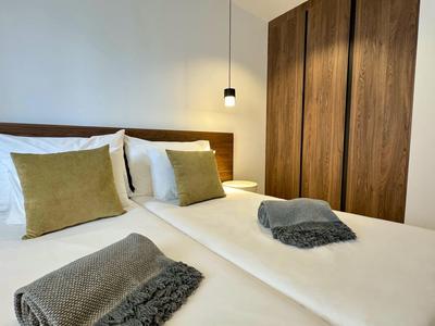 Camera d'hotel moderna con due letti singoli, cuscini rustici e armadio in legno.