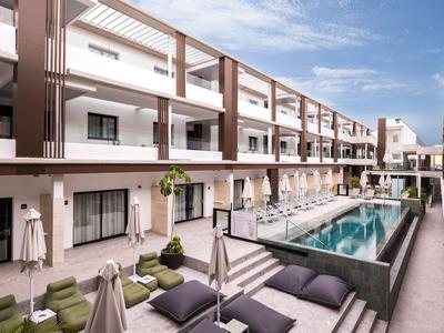 Modern hotel complex with a central pool and comfortable sun loungers.