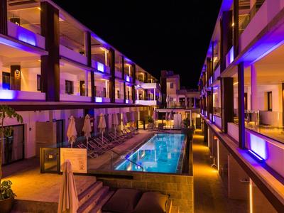 Hotel moderno con piscina illuminata e balconi di notte.