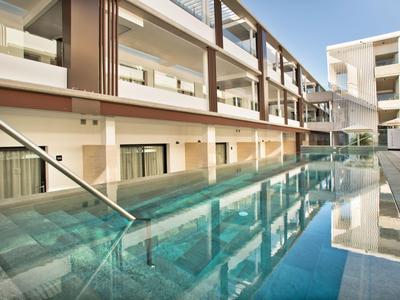 Piscina moderna dell'hotel con scale e riflesso dell'edificio sotto un cielo limpido