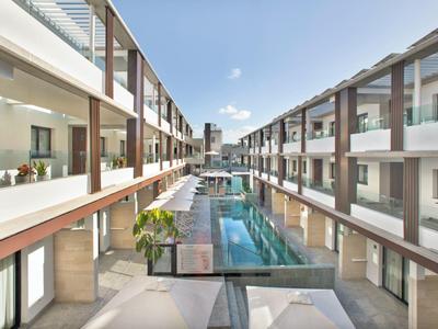 Complesso alberghiero moderno con piscina centrale e camere su due piani su entrambi i lati.