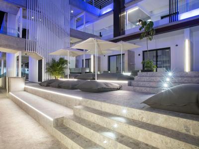 Modern hotel courtyard with stairs, cushions, and illuminated steps at night.