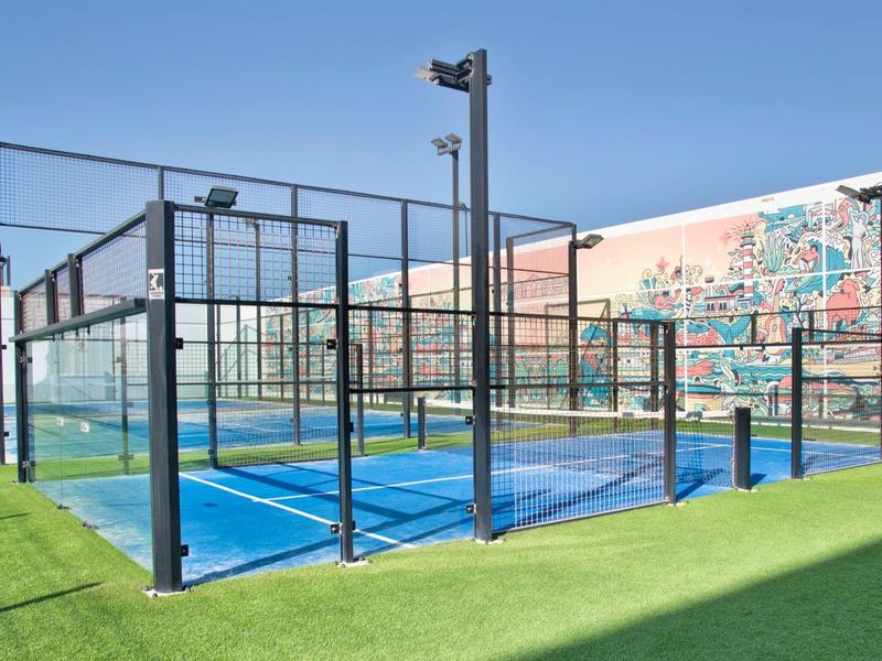 Campi da paddle tennis all'aperto con pavimenti blu e contorni verdi in una struttura sportiva.