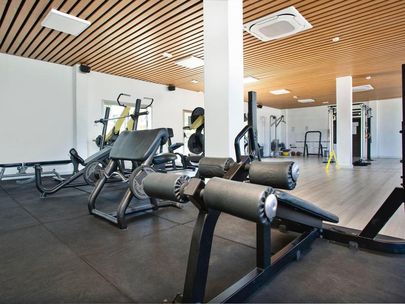 Palestra moderna con varie attrezzature per allenamento e accenti di soffitto in legno chiaro.