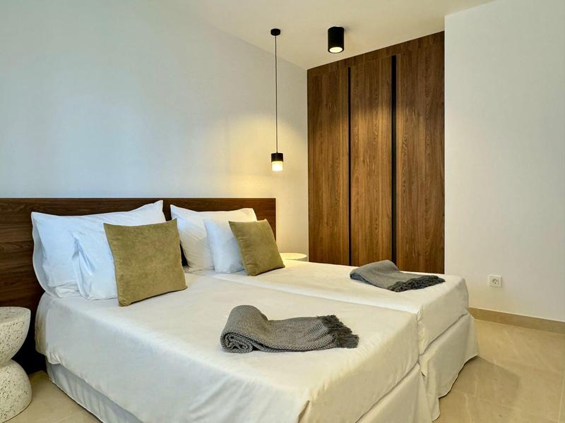 Camera d'albergo luminosa con due letti singoli e mobili in legno.