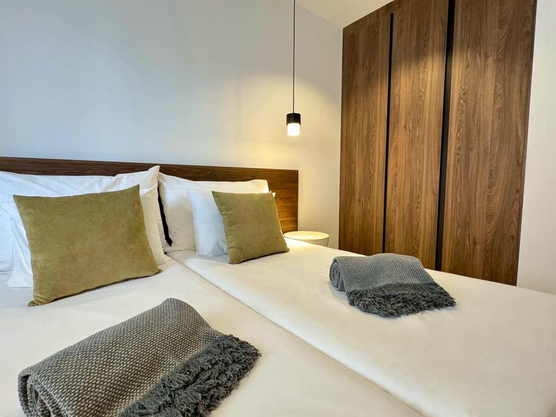 Camera d'hotel moderna con due letti singoli, cuscini rustici e armadio in legno.