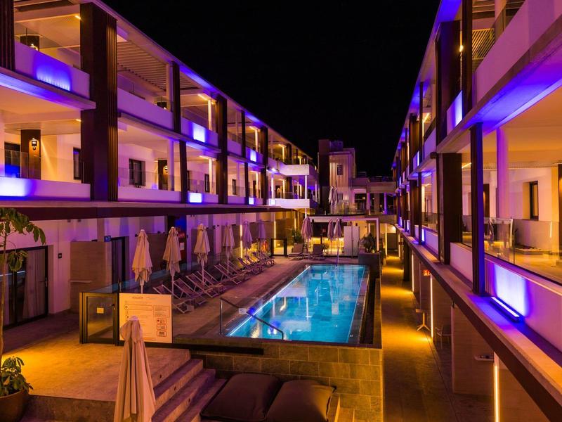 Hotel moderno con piscina illuminata e balconi di notte.