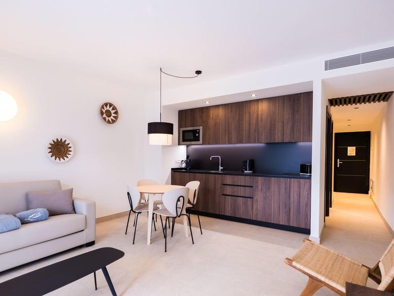 Zona giorno moderna con cucina a vista, tavolo da pranzo e comoda area divano.